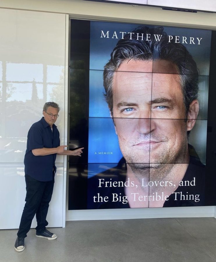 Matthew Perry seems all sorts of happy alongside a picture of his polarizing memoir.