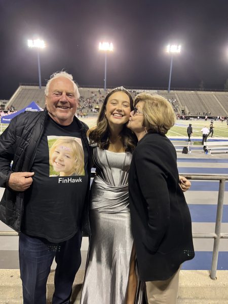 Senior Finley Hawkins smiling for a picture with her grandparents who came to support her at the Homecoming football game.