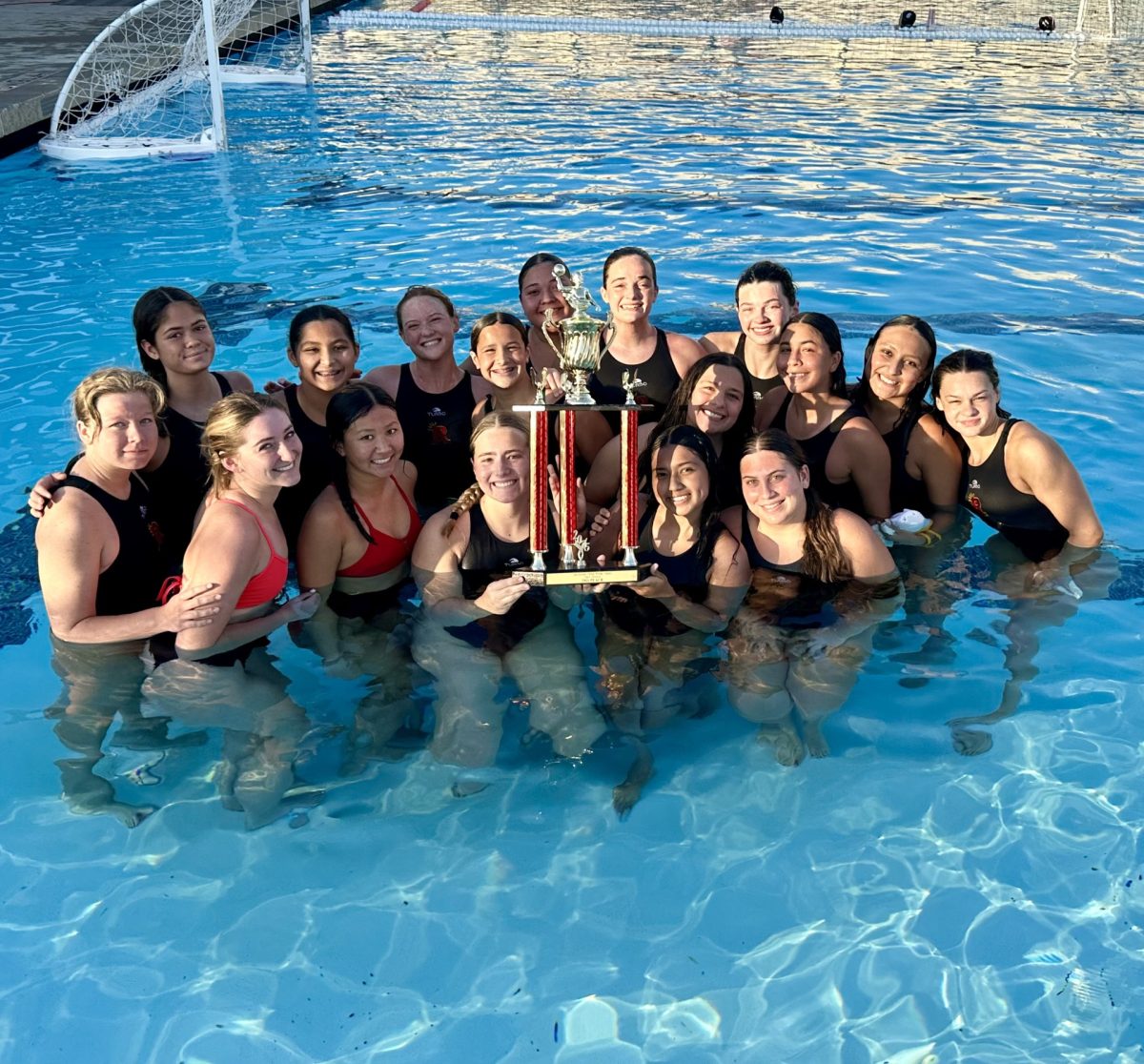 The water polo team snaps a picture with their trophy.