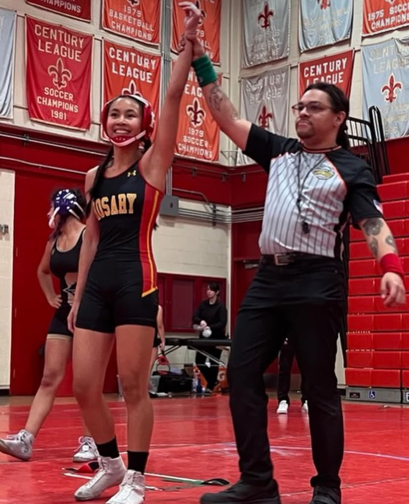Abby Chu '29 raises her hand in victory at a wrestling tournament.